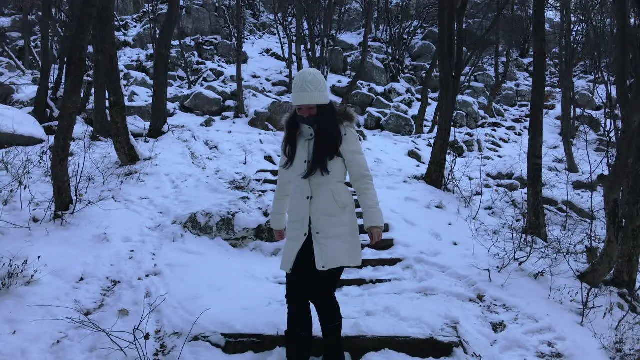 Woman climbing down snowy stairs in the mountain Extremely wide shot