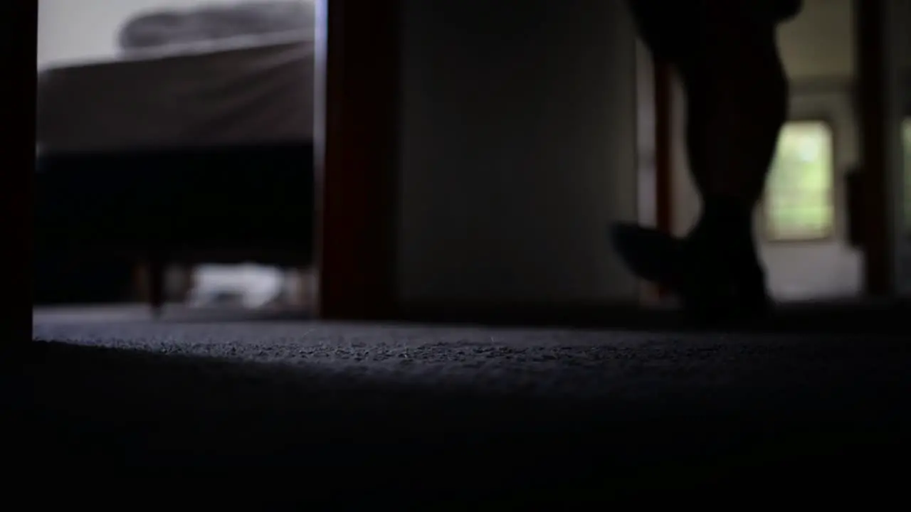 Young man in dark hallway approaching the ground level camera then entering a bedroom and closing the door behind him