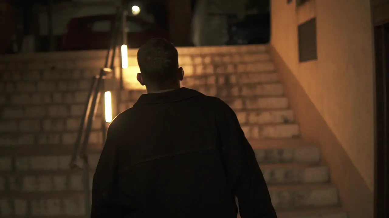 Slow Motion Shot Of Man Walking Towards Lighted Stairs Going Up