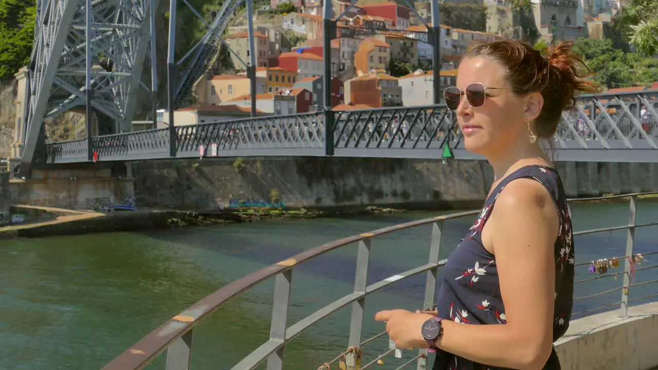 Red haired tourist girl taking fotos of the old town of Porto in Portugal famous Bridge in the background