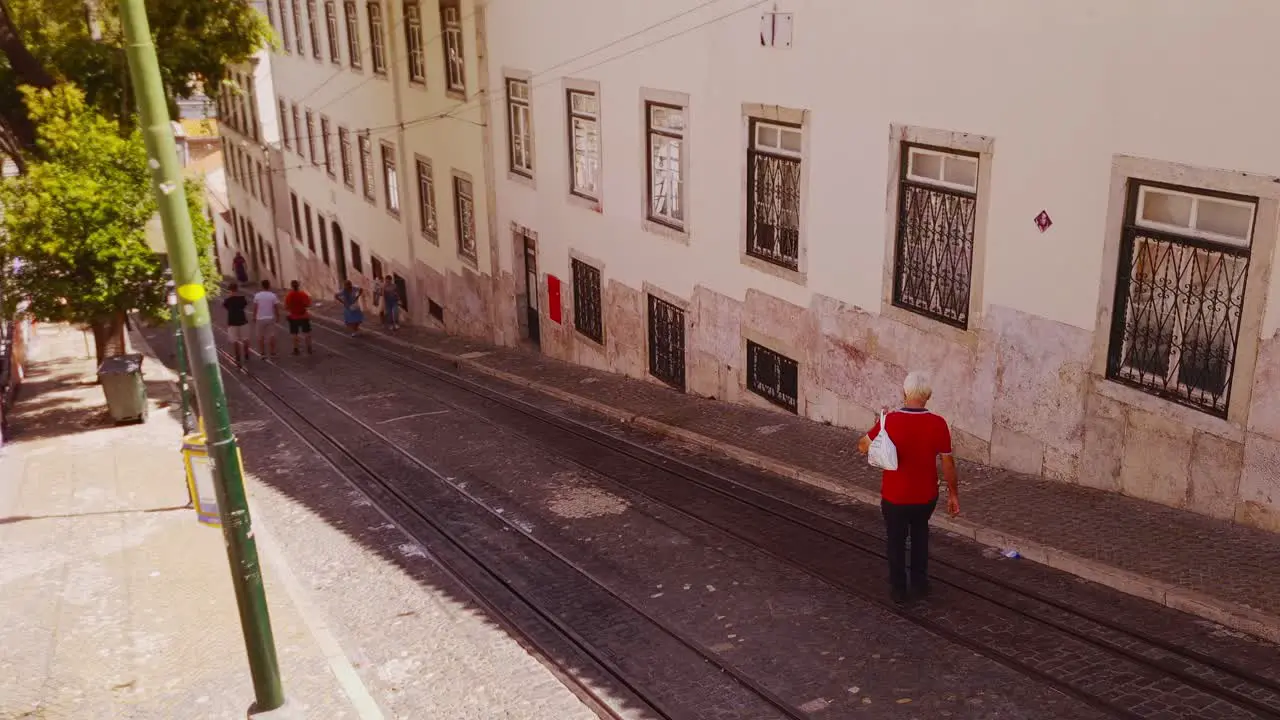 Residents of Lisbon make their up and down a city slope crossing tram tracks