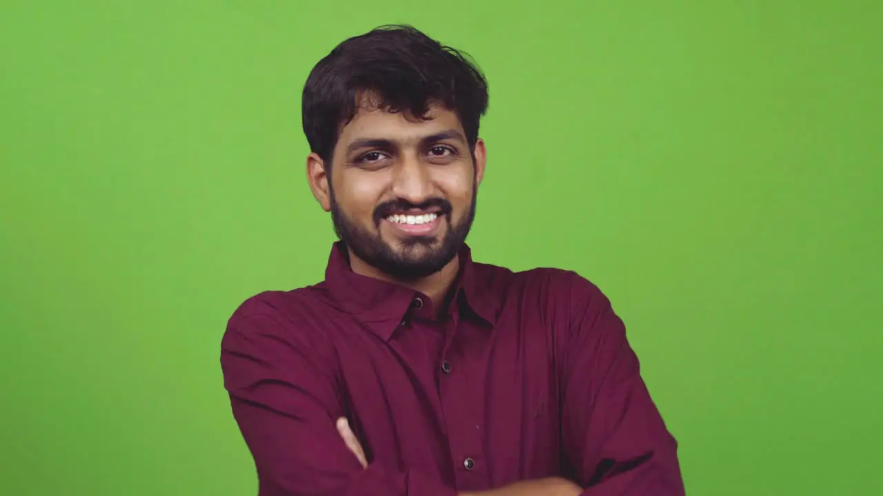 Attractive and sexy Indian guy looking towards camera and smiles isolated on green screen