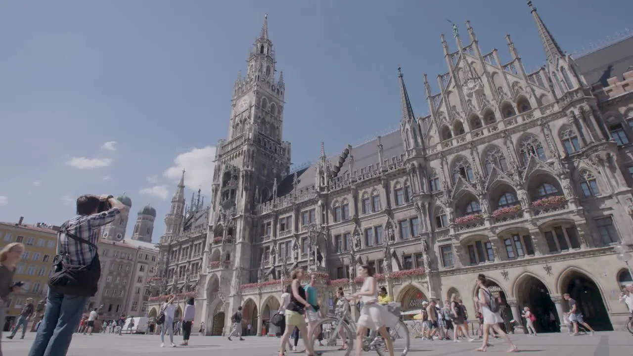 Handheld shot of people strolling in front of a grand cathedral on a sunny day in Munich Germany