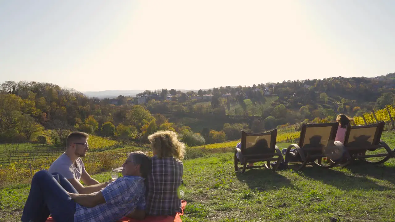 tourists sitting in vineyards grass with background forest still eye level shot