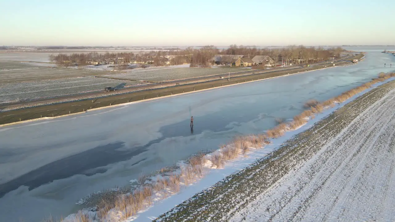 Person ice skating on natural frozen river in flat land of Holland winter