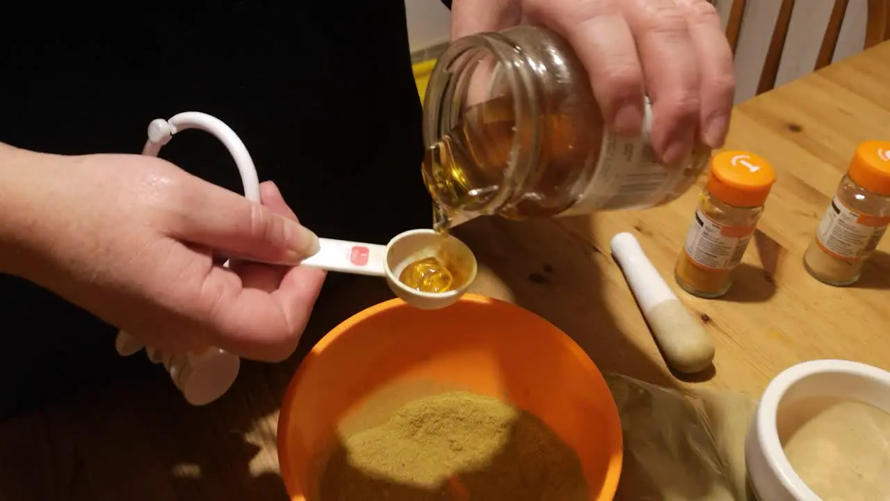 Female measures honey with Moringa and turmeric powder herbal medicine supplement in kitchen