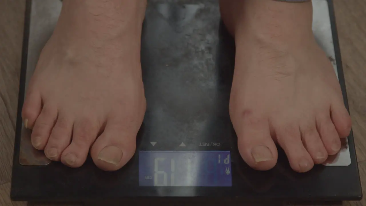 Close up of bare feet stepping on weight scale