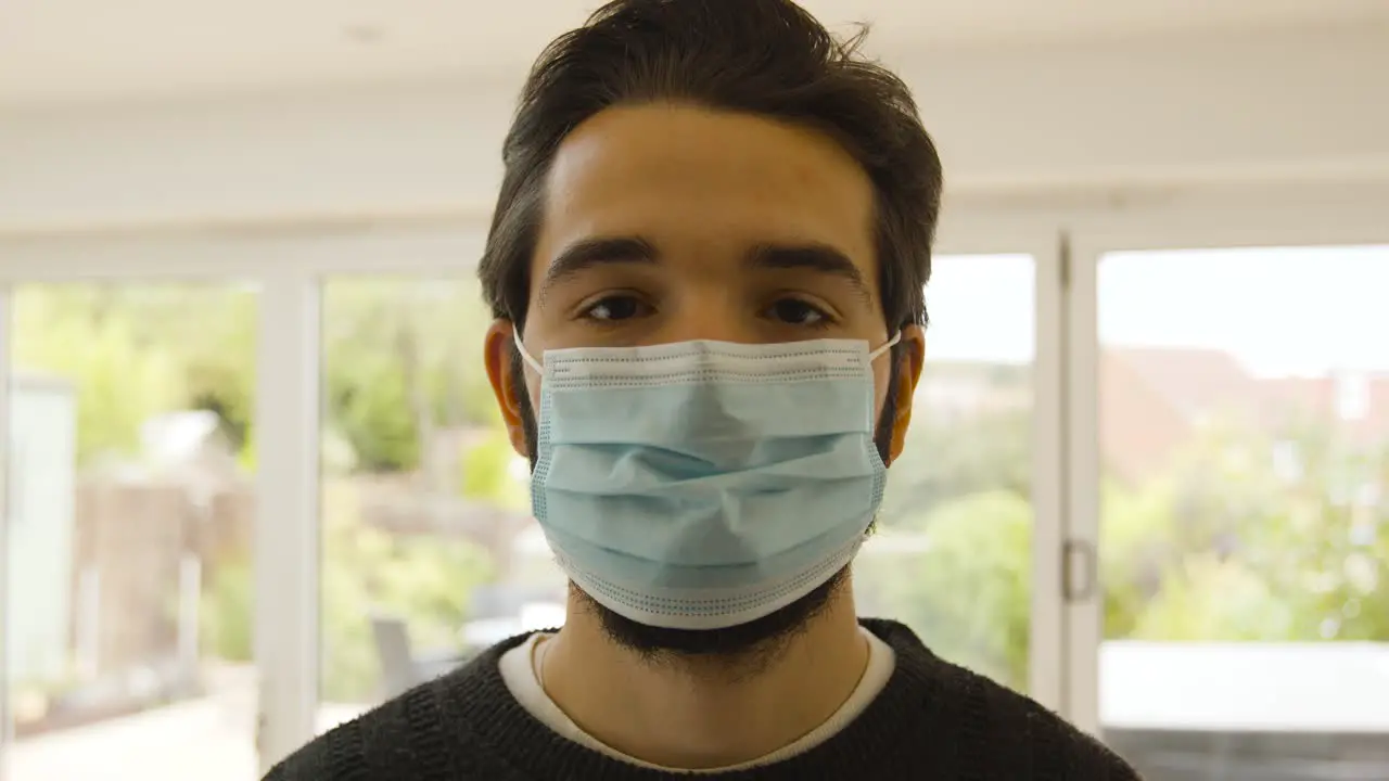 Male looking plainly at camera and putting on a facemask