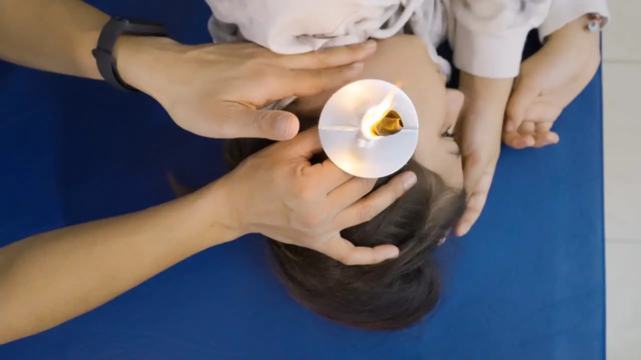 Top-down view of a young girl during an ear candling session