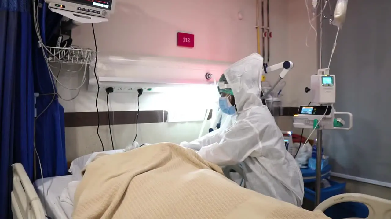 Doctor Tending To Covid-19 Patient Lying In A Hospital Bed