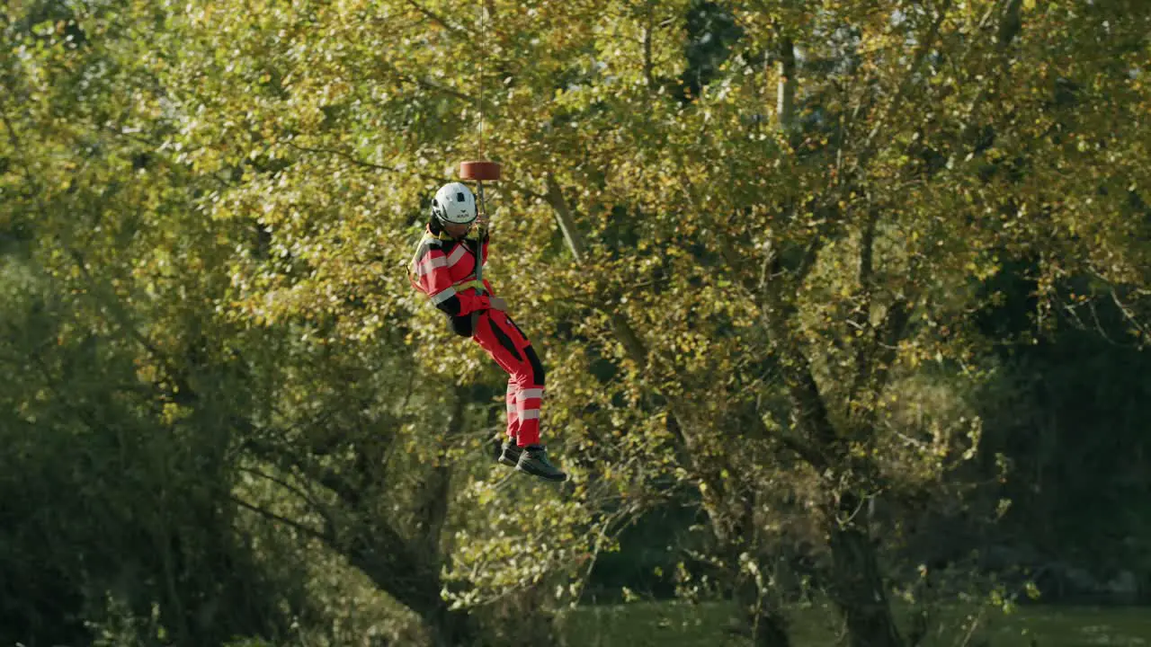 Rescuer hanging in the air from Helicopter hook and landing- sunny day slowmotion