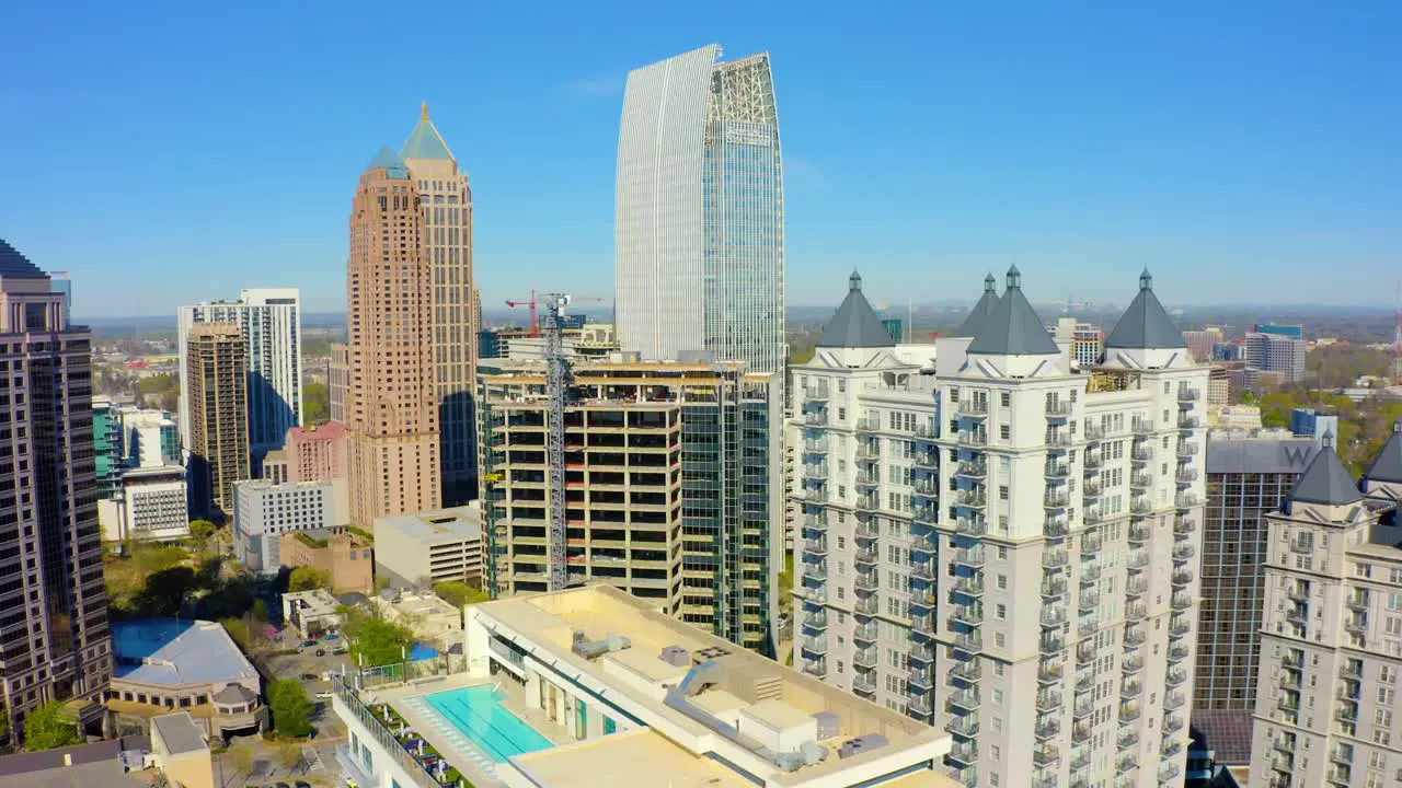 Aerial drone shot slowly rotating counter-clockwise around skyscrapers near Piedmont Park in Midtown near downtown Atlanta Georgia on a sunny day with blue skies