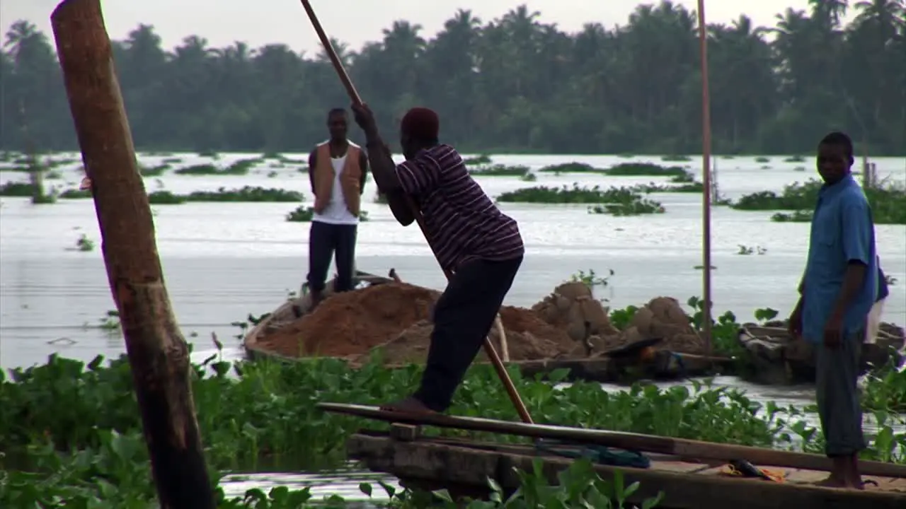 Nigeria men transporting sand on a river boat