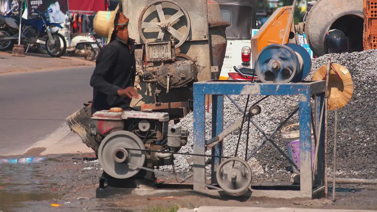 Medium Shot of a Worker Supervising a Gasoline Powered Pulley Machine at the Construction Site