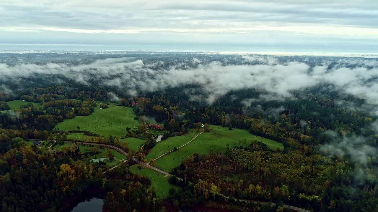 Aerial drone shot flying above lush green tropical rain forest landscape with white clouds cover during the rainy season in the countryside