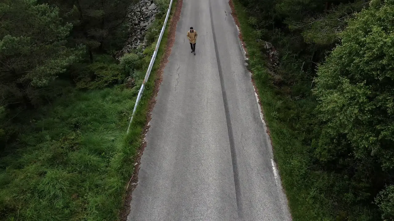 Aerial top down shot of person walking on street in forest landscape of Norway