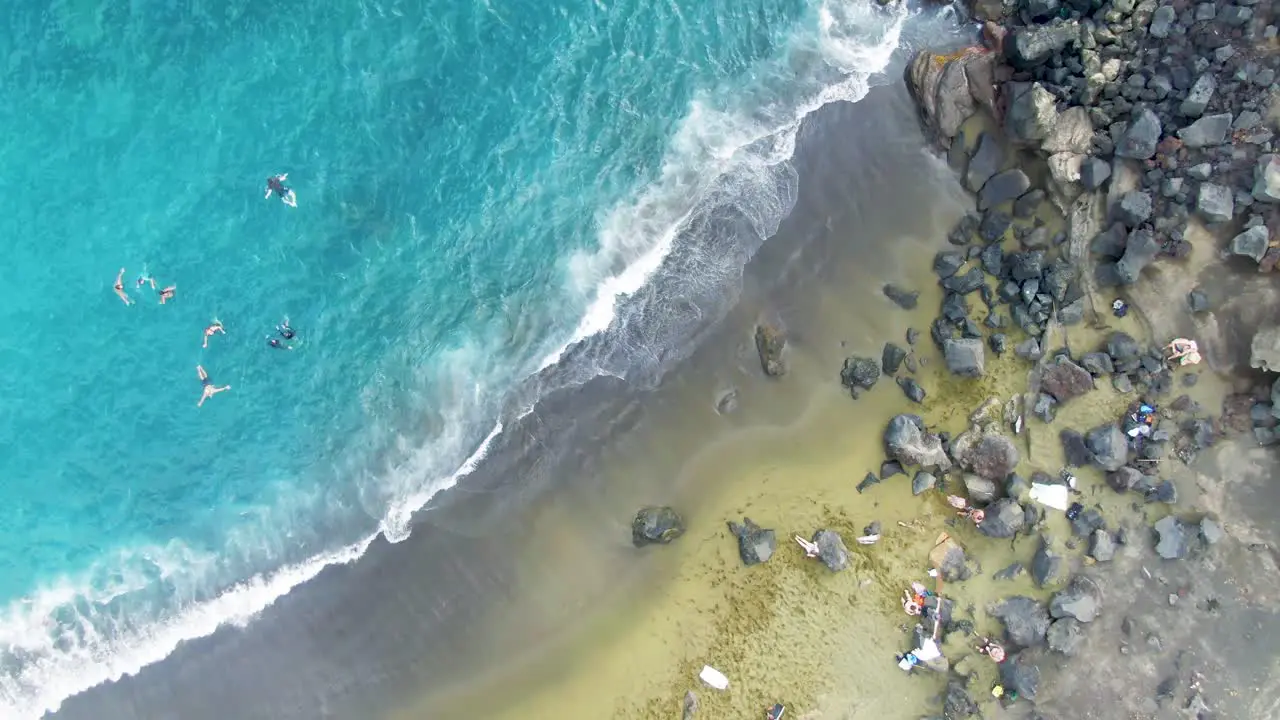 People swim by Papakolea Beach in Hawaii spinning overhead aerial