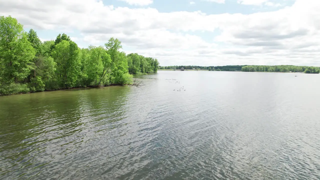 Aerial drone forward moving shot over lake surrounded by beautiful green forest