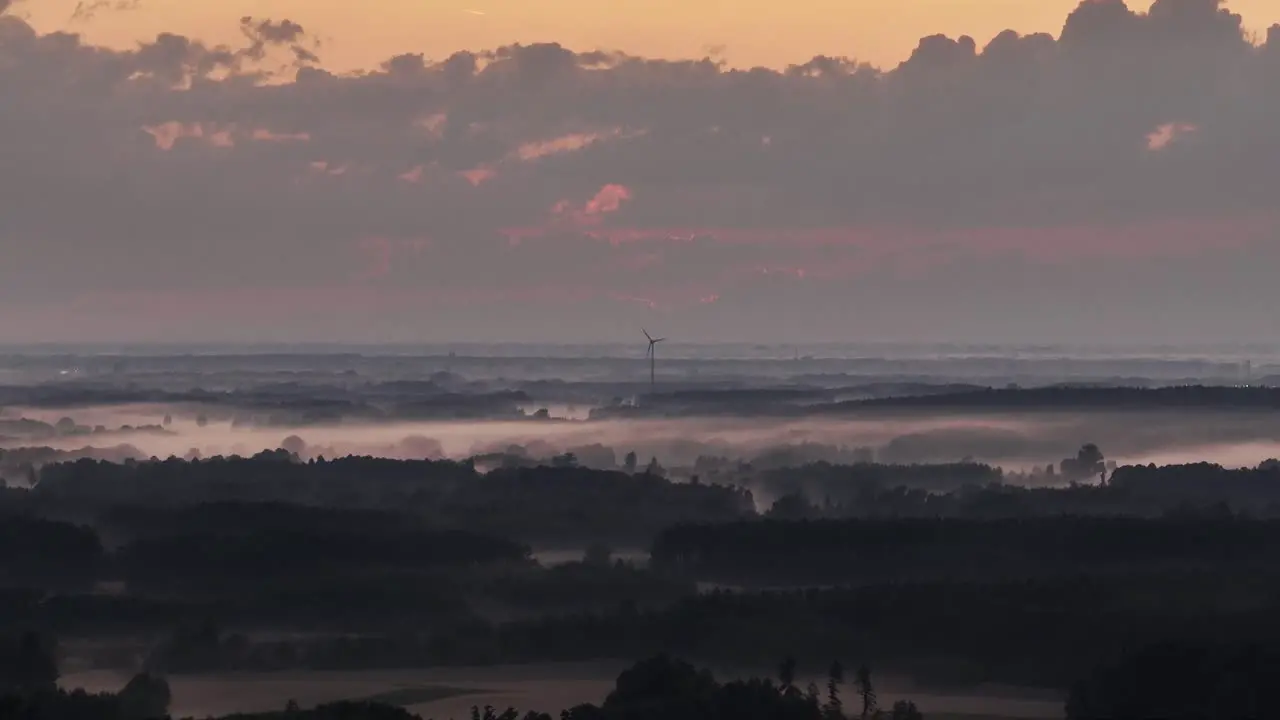 aerial view of natural landscape at foggy sunrise with windmill wind turbine