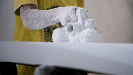 Handheld Long Shot of a Surfboard Shaper Using Power Tool On Polystyrene Surfboard