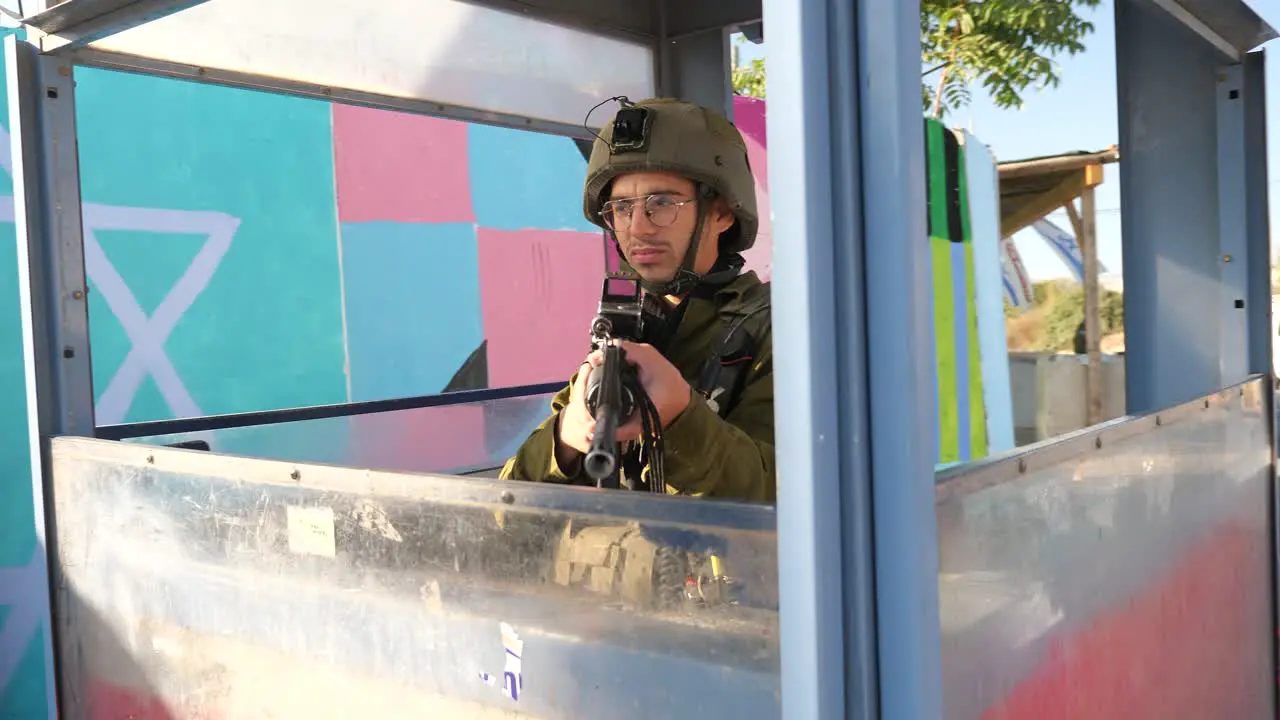 Touch looking Israeli soldier holding rifle in checkpoint cabin