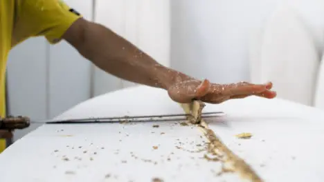 Handheld Close Up Shot of Surfboard Shaper Cutting Wood Away from Polystyrene Board