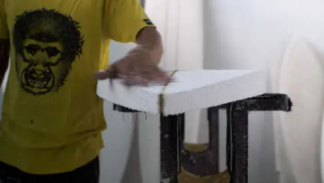 Handheld Medium Shot of Surfboard Shaper Brushing Away Excess Polystyrene