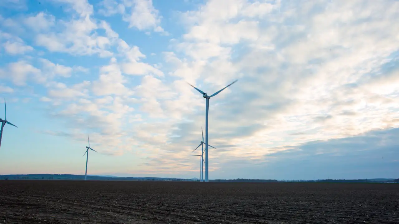 Time lapse of a windmill farm silhouette in country fields on a cloudy dusk