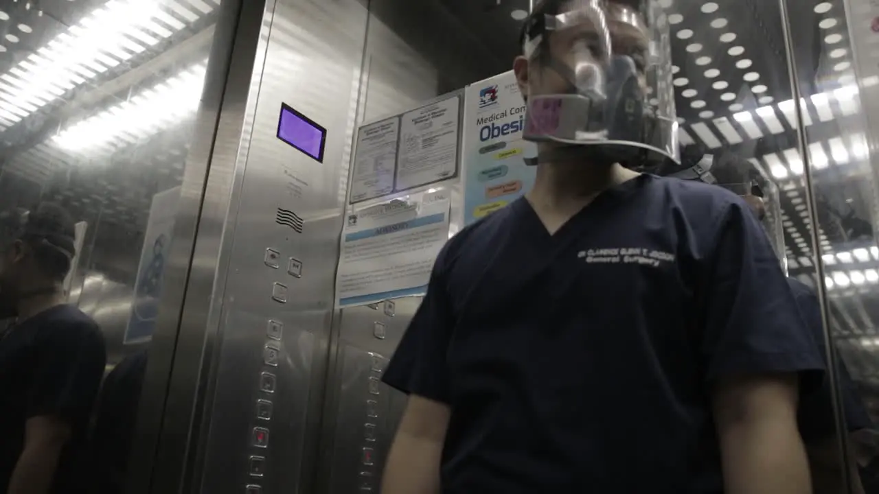 Doctor Wearing Respirator and Face Shield Pushing Button in Hospital Elevator