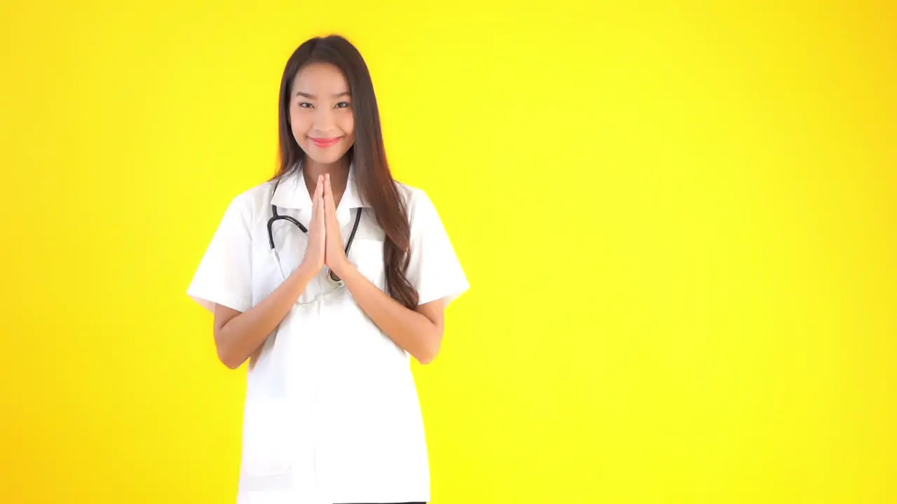 A female healthcare worker with a stethoscope around her neck raises her hands in the prayer position