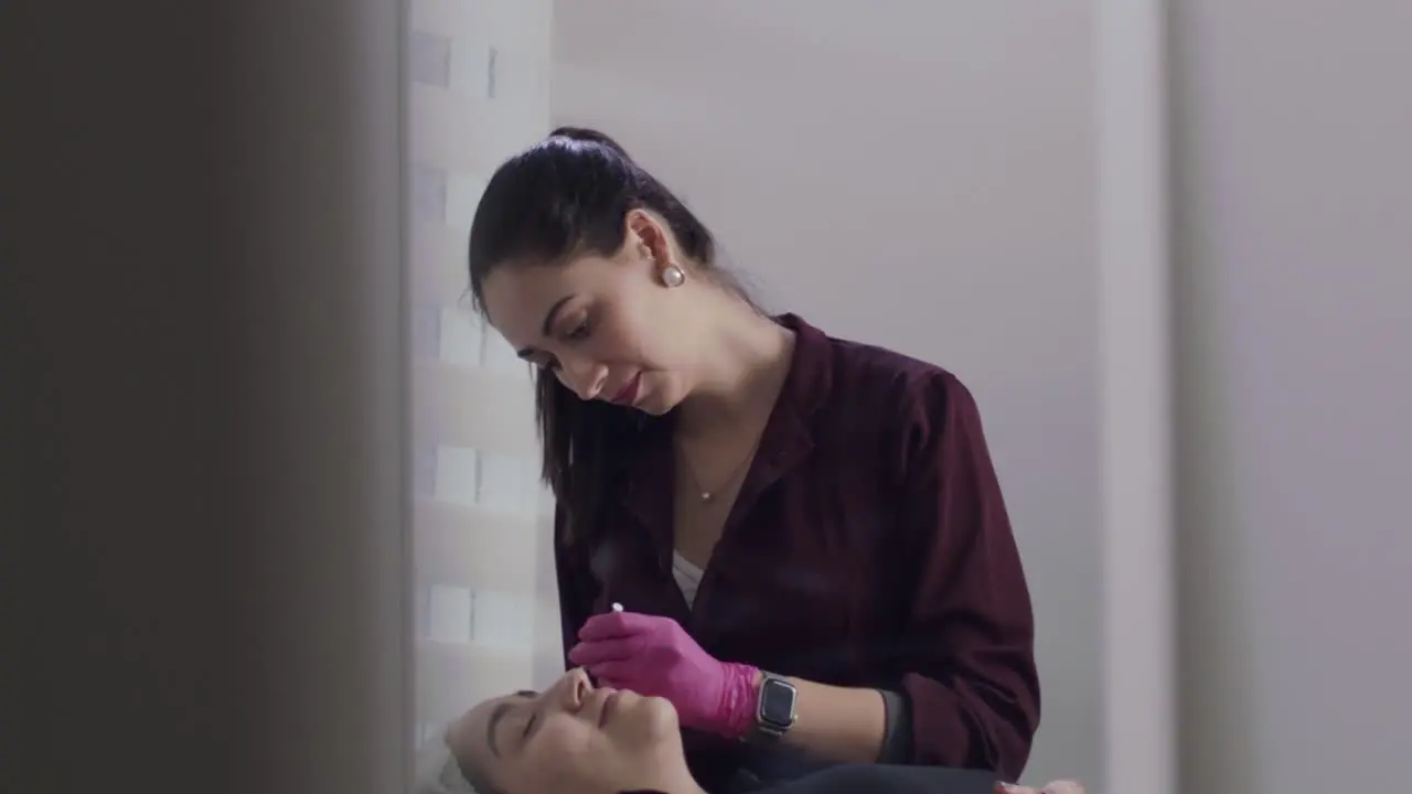 Cosmetic surgeon woman injecting botox into patient's face in her private clinic slow motion