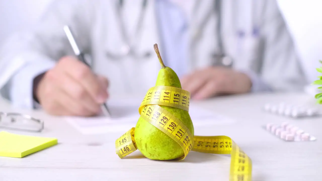 Fruit as Healthy eating concept Doctor taking notes pear and measure tape