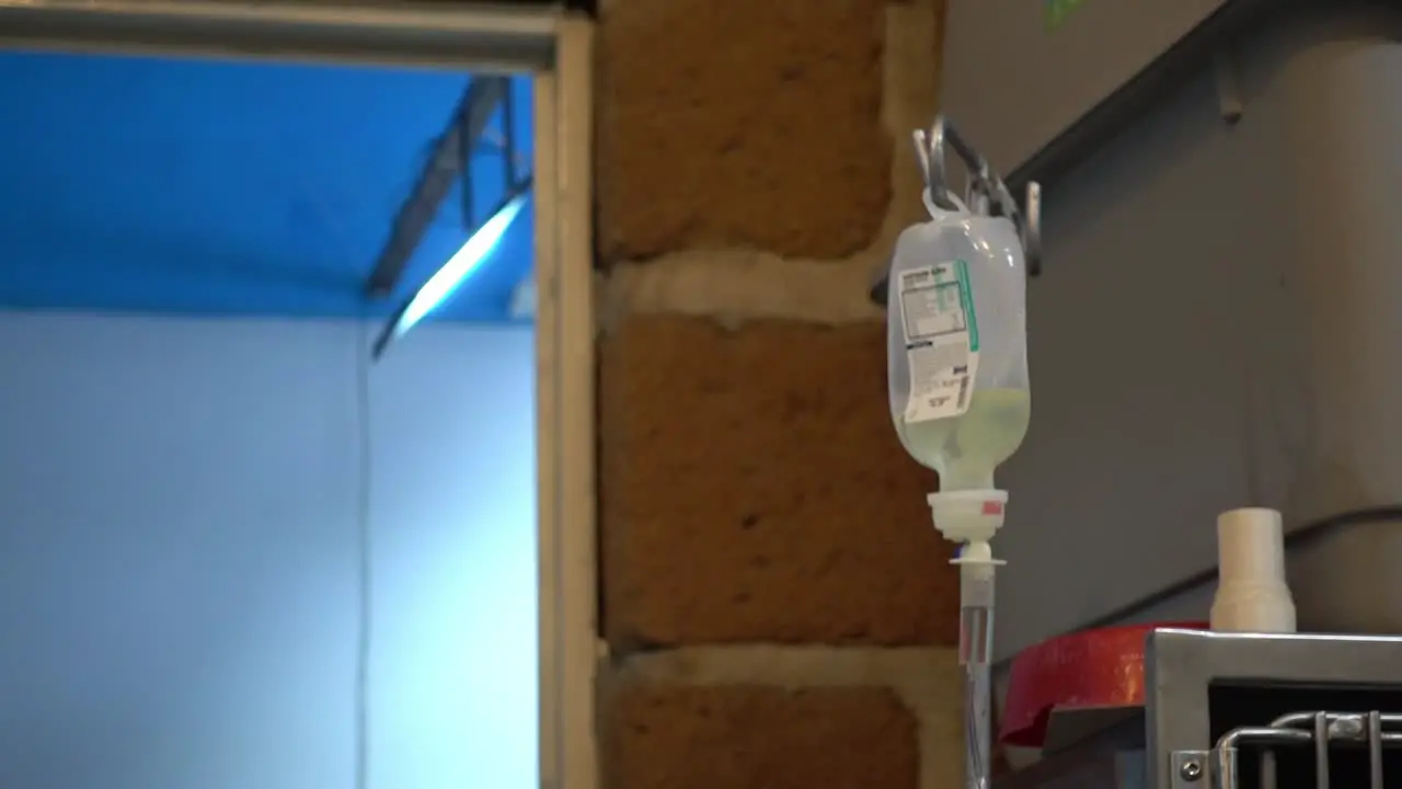 Hand-held shot of intravenous fluids dripping through the line delivering medication