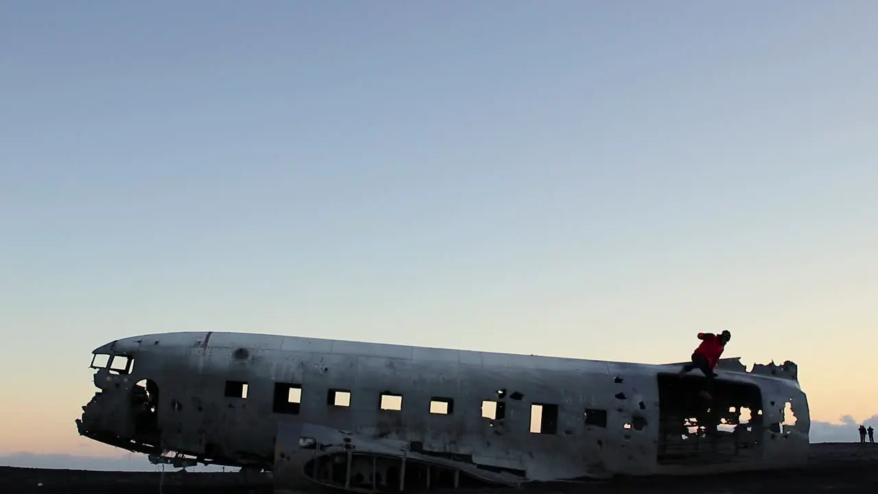 Crashed plane in southern Iceland outside Vik at a black sand beach during sunset and jumping down