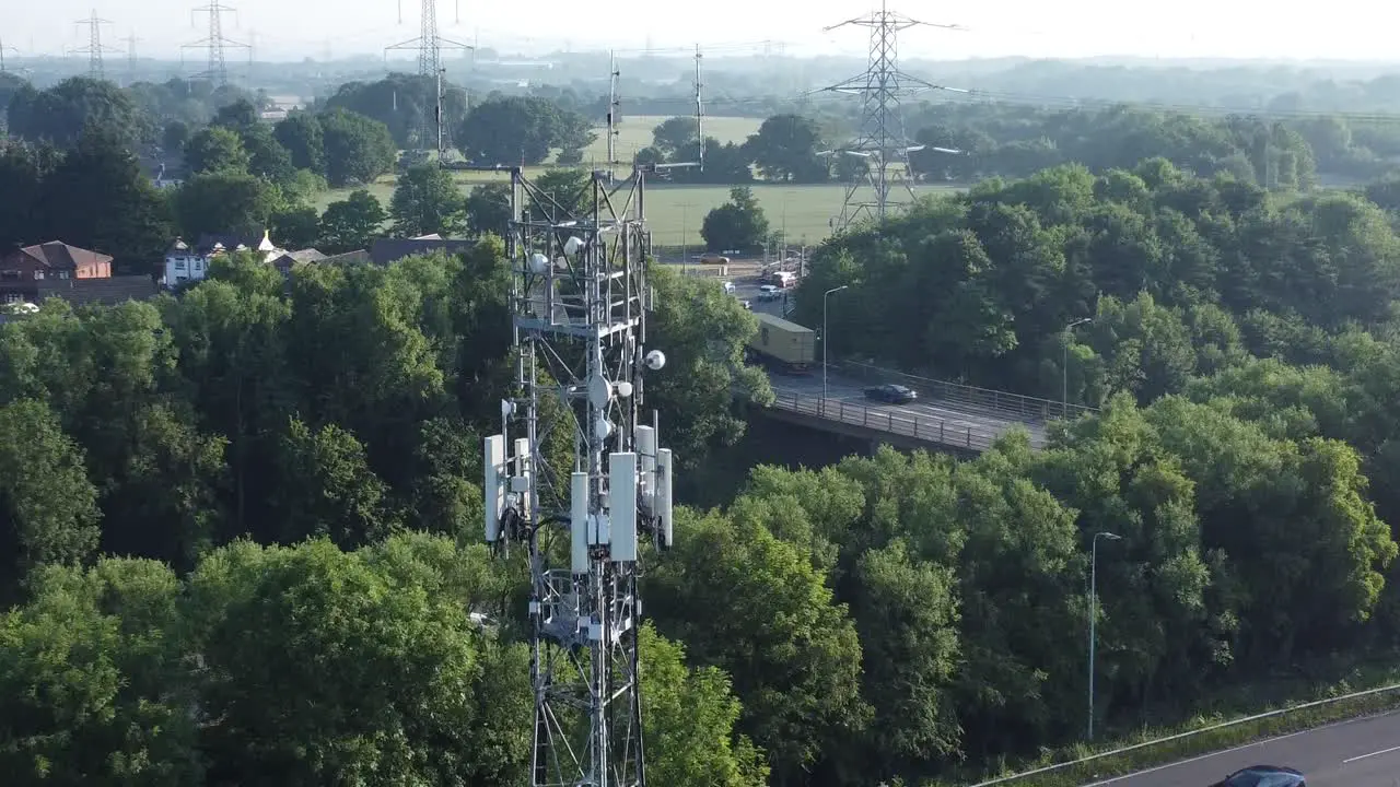 5G broadcasting tower antenna in British countryside with vehicles travelling on highway background