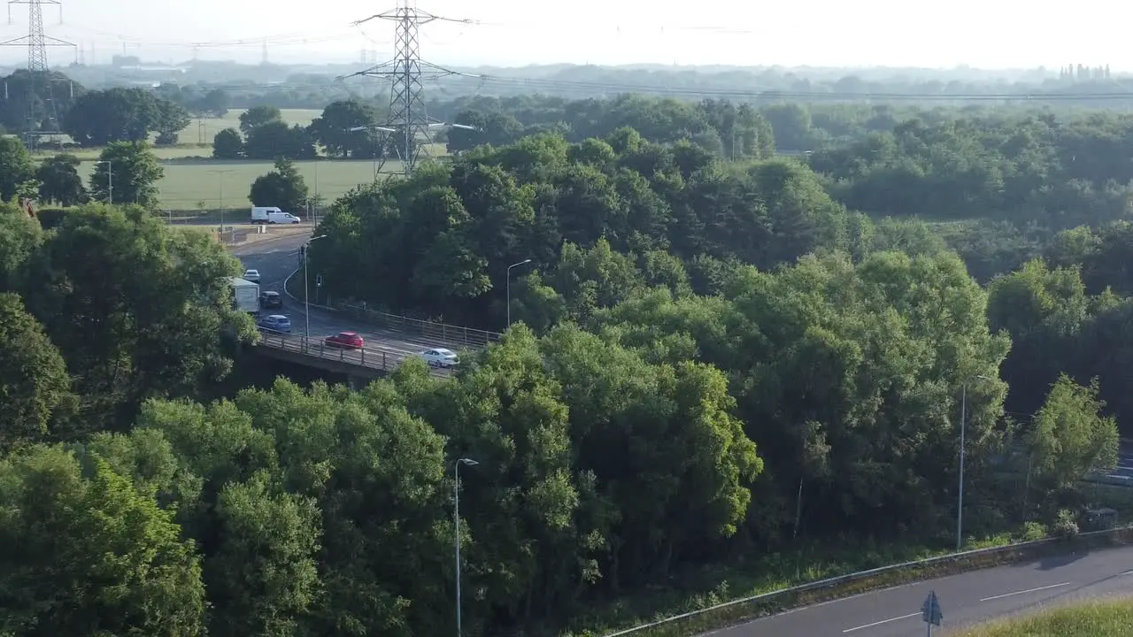 Vehicles travelling on highway background aerial descend to 5G broadcasting tower antenna in British countryside