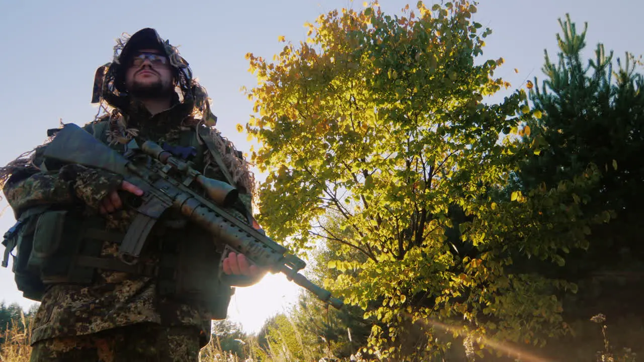 Man In Camouflage With Guns It Should Be Against The Sky The Sun Shines On His Gun Lower Angle Shoot