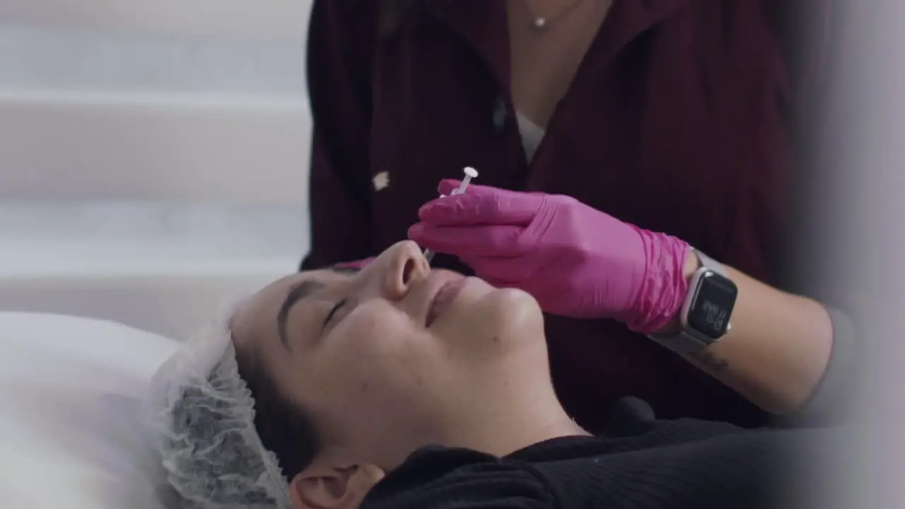 Cosmetic surgeon injecting botox into patient's face inside her clinic slow motion