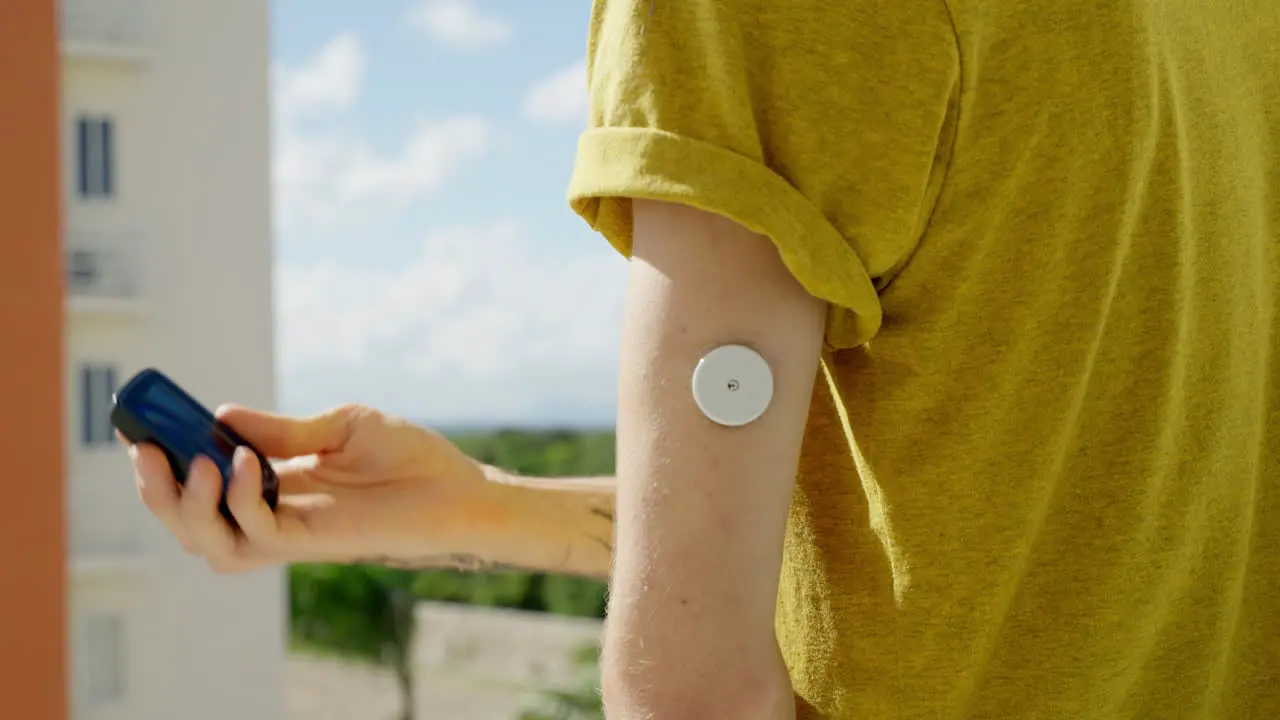 Young Adult Male Checking His Blood Glucose Levels On Left Arm With Freestyle Libre 2 Sensor