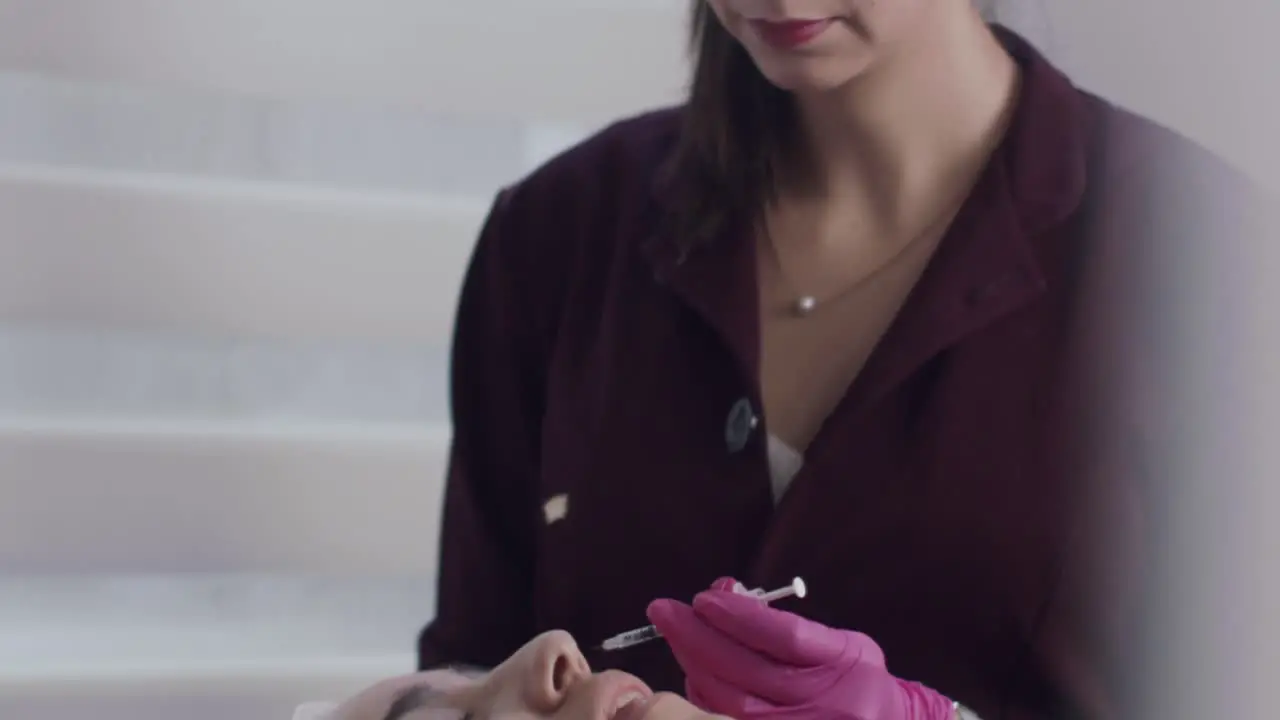 Beautician preparing to inject botox into patient's face inside clinic slow motion