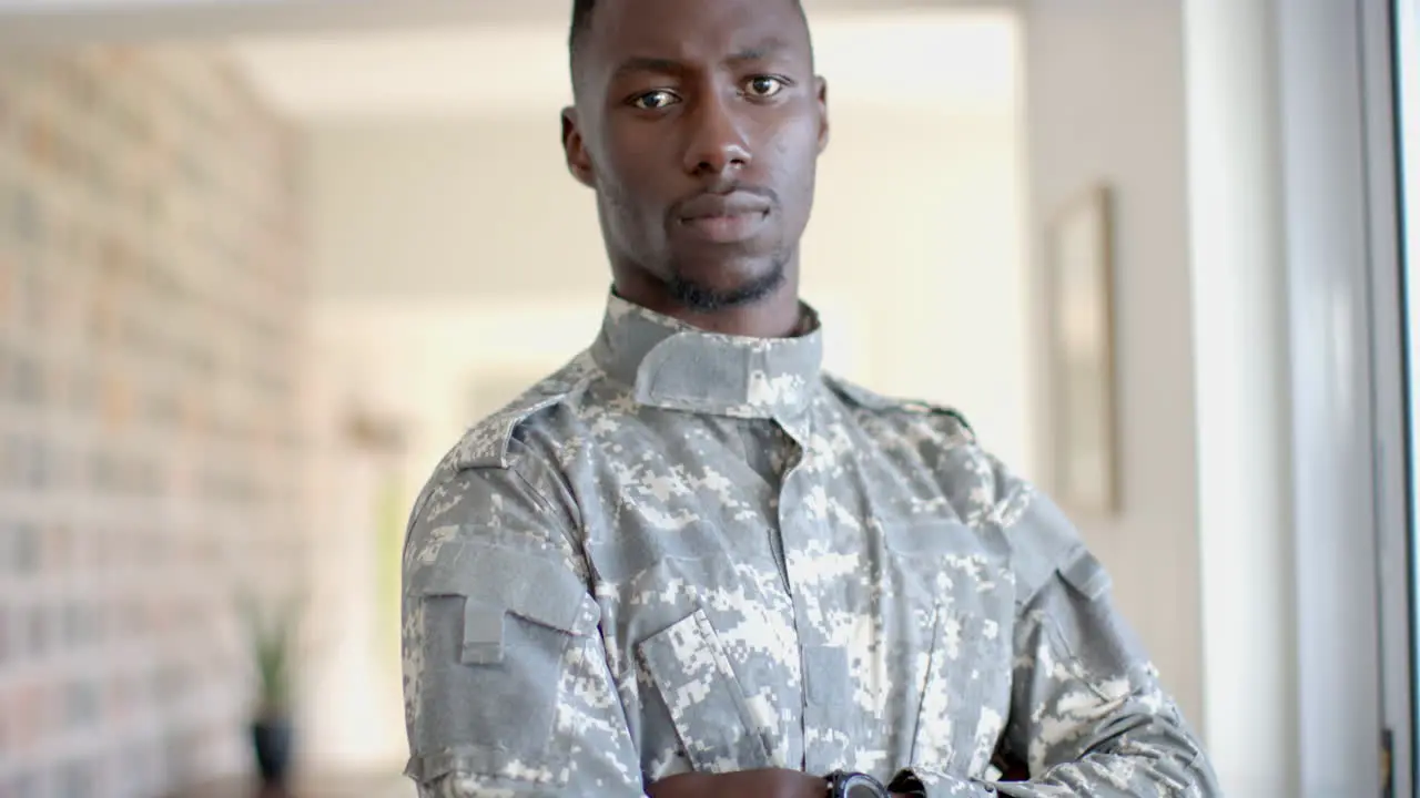 Young African American soldier in military uniform stands confidently at home