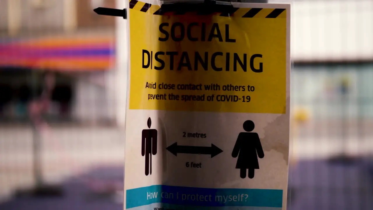 A small dolly out to expose the title of the social distancing sign