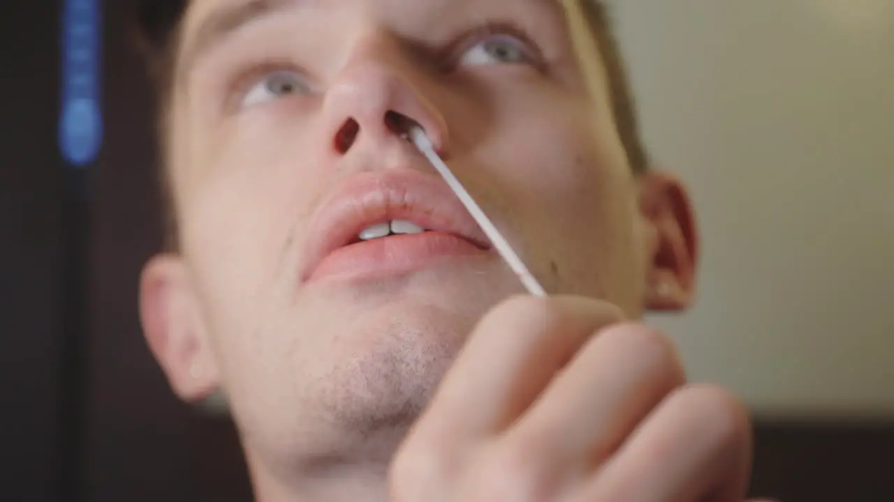 Man Rotating Sterile Nasal Swab Around Its Nostril COVID-19 Test Kit At Home