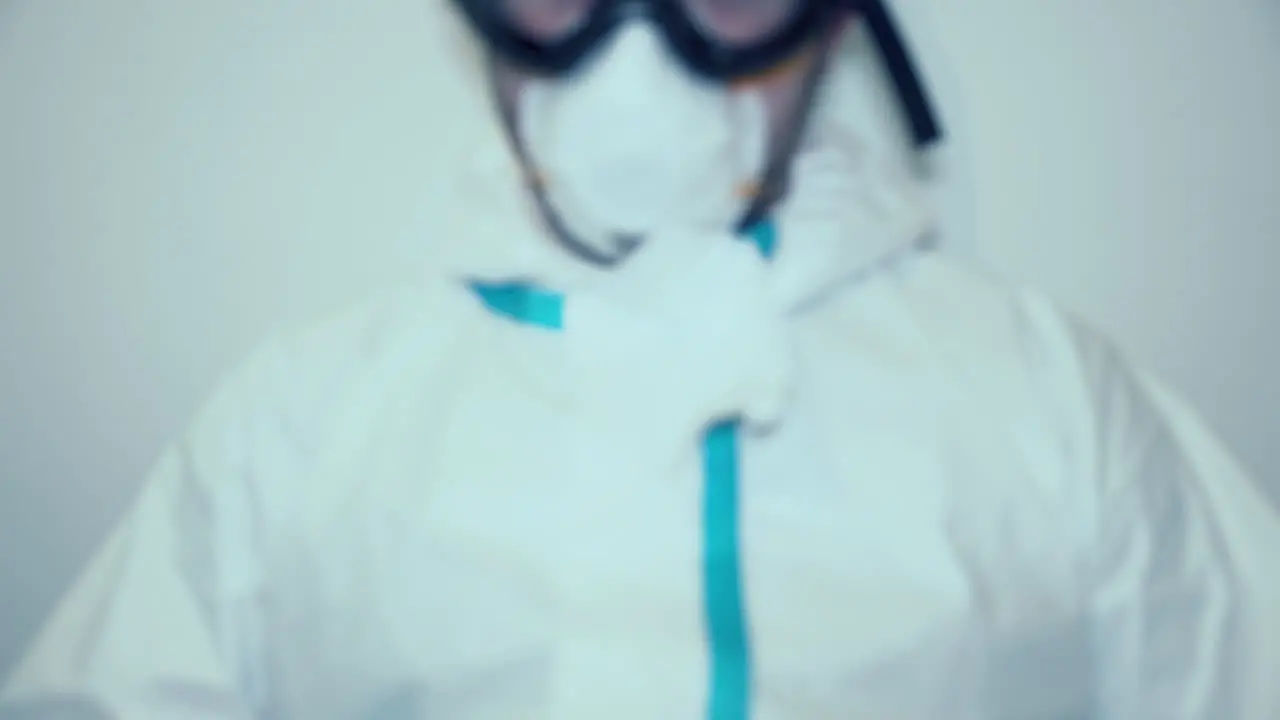 Exhausted Healthcare Worker In Protective Suit Breathing Heavily After Long Hours Of Duty out of focus shot