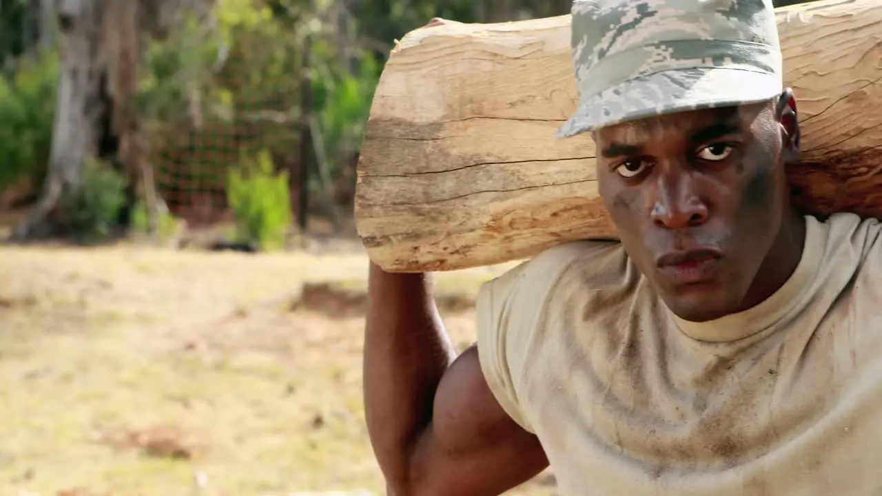 Fit man carrying heavy wooden log while exercising