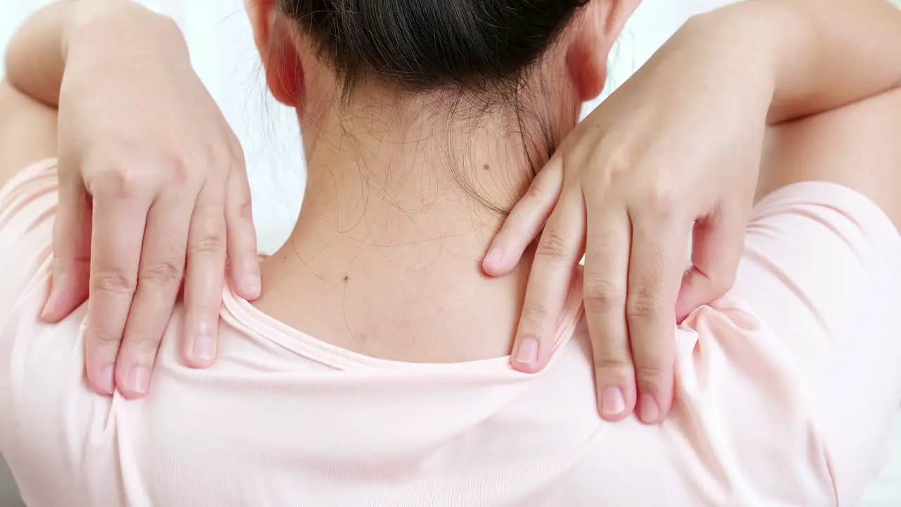 Tired woman massaging rubbing stiff sore neck tensed muscles fatigued from work in incorrect posture feeling hurt joint shoulder back pain ache close up rearview