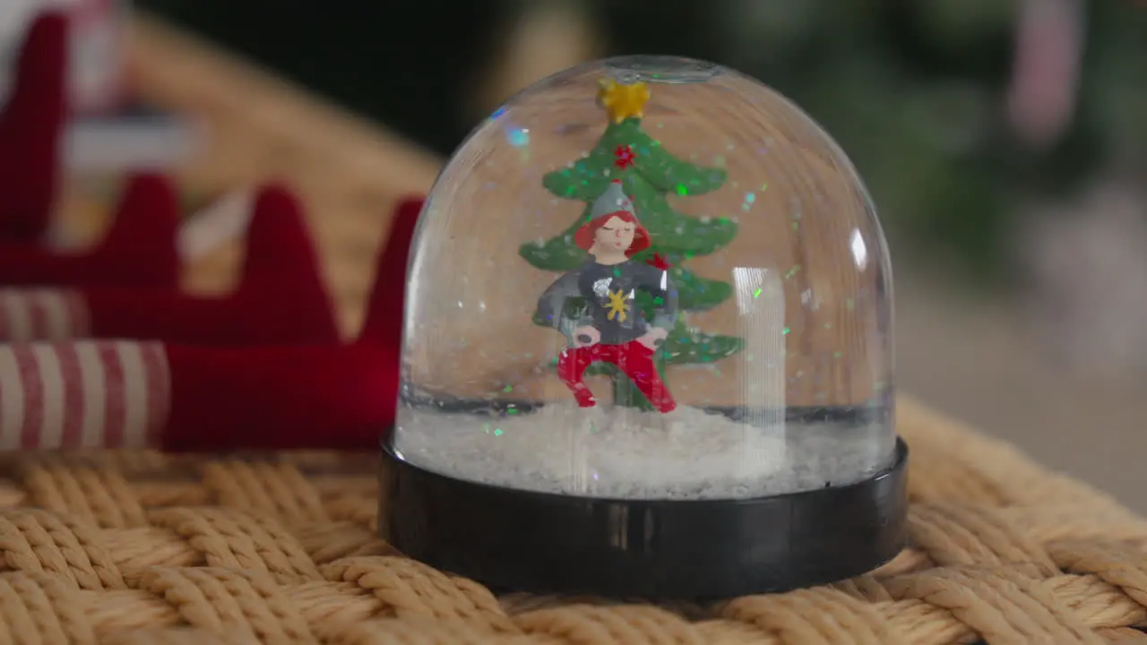 Snow globe with a festive figurine and Christmas tree on a woven mat