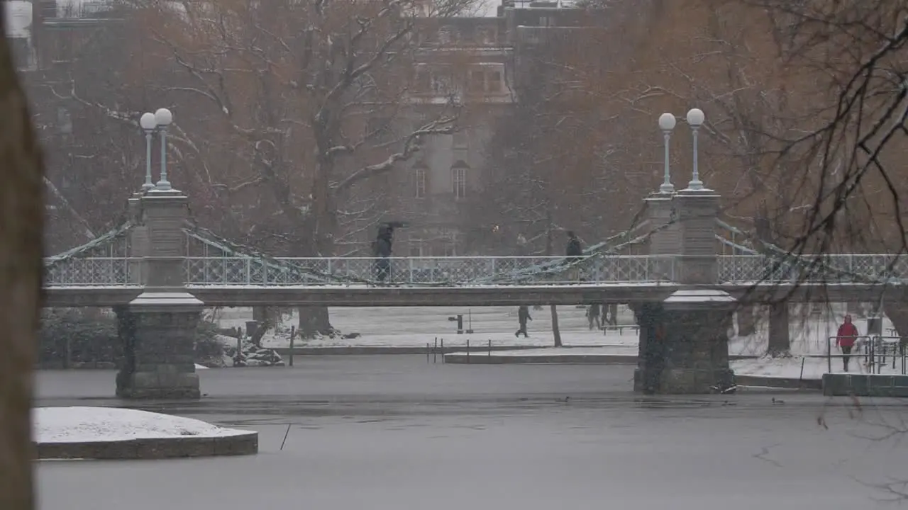 Slow motion of people walking across footbridge on a snowy day in Boston