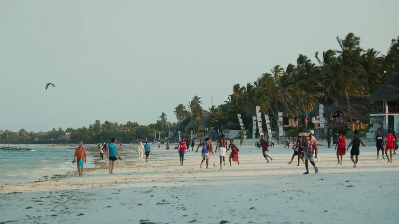 Beach scene with people and kite surfers at sunset