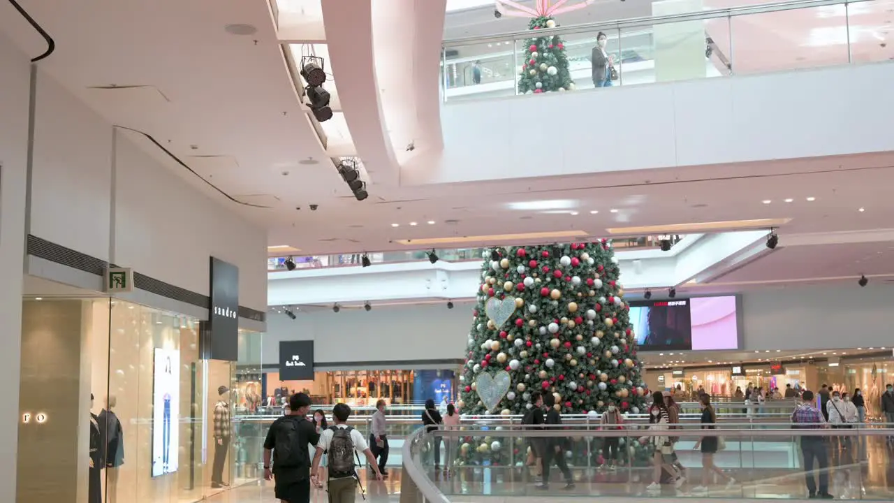 Chinese shoppers walk through a shopping mall as a large-size Christmas tree installation is seen in the background in Hong Kong